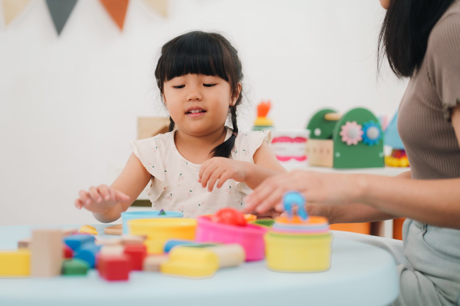 Girl, play, toy, table, adult hand guiding child learning activity Child playing with colorful learning toys with an adult